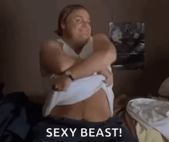 A Woman Is Sitting On A Bed Taking Off Her Shirt And Says `` Sexy Beast '' . GIF