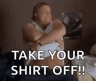 A Woman Is Sitting On A Bed Taking Off Her Shirt And Says `` Take Your Shirt Off ! '' GIF