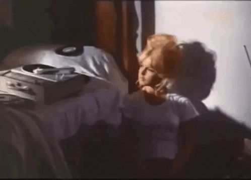 A Woman Is Sitting On A Bed Talking On A Cell Phone . GIF