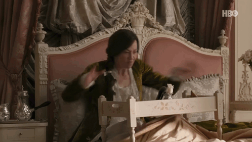 A Woman Is Sitting On A Bed With A Tray In Front Of Her That Says Hbo On The Bottom GIF