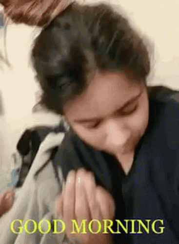 A Woman Is Sitting On A Bed With Her Hair In A Bun And A Good Morning Message . GIF
