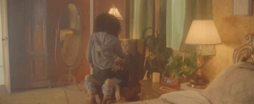 A Woman Is Sitting On A Chair With A Child In A Bedroom . GIF