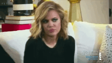 A Woman Is Sitting On A Couch And Making A Funny Face GIF