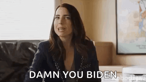 A Woman Is Sitting On A Couch And Saying `` Damn You Biden '' While Looking At The Camera . GIF