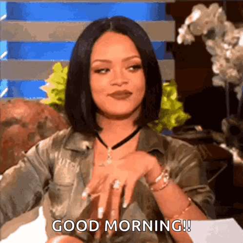 A Woman Is Sitting On A Couch And Saying `` Good Morning '' While Wearing A Choker . GIF