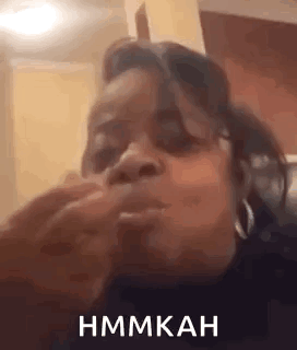 A Woman Is Sitting On A Couch Eating A Sandwich And Making A Funny Face . GIF