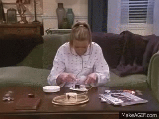 A Woman Is Sitting On A Couch Eating Cake On A Table . GIF