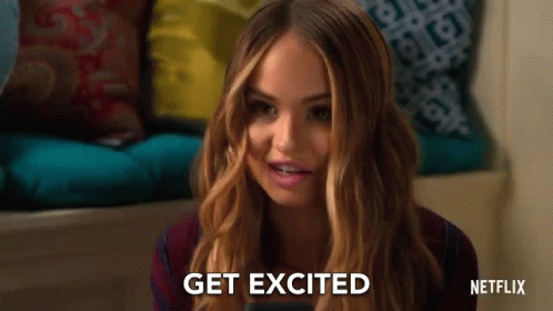 A Woman Is Sitting On A Couch Holding A Cell Phone And Smiling . GIF