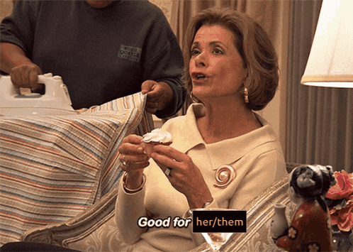 A Woman Is Sitting On A Couch Holding A Cupcake And Saying " Good For Her / Them " GIF