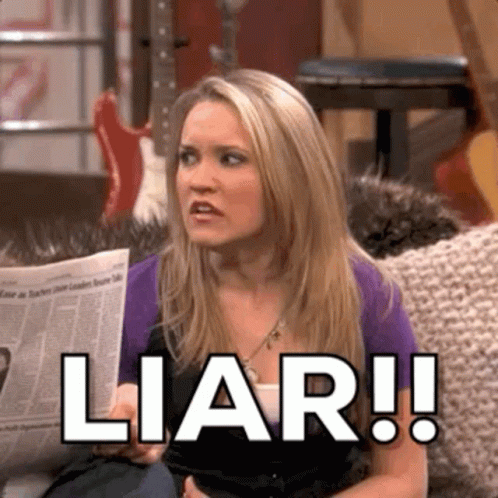 A Woman Is Sitting On A Couch Holding A Newspaper And Saying Liar . GIF