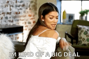 A Woman Is Sitting On A Couch In A Living Room Holding A Book And Saying `` Im Kind Of A Big Deal '' GIF