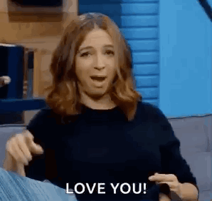A Woman Is Sitting On A Couch Making A Funny Face And Saying `` I Love You '' . GIF