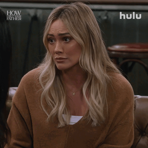 a woman is sitting on a couch with a hulu logo in the background