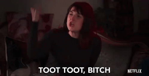 A Woman Is Sitting On A Couch With Her Fist In The Air And Saying Toot Toot Bitch . GIF