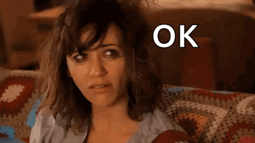 A Woman Is Sitting On A Couch With Her Hair Blowing In The Wind And The Words `` Ok Hot Mess '' Above Her . GIF