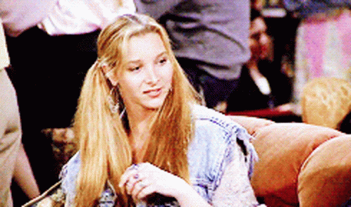 A Woman Is Sitting On A Couch With Her Hair In Pigtails GIF
