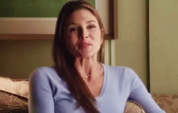 A Woman Is Sitting On A Couch With Her Hand On Her Chin And Looking At The Camera . GIF