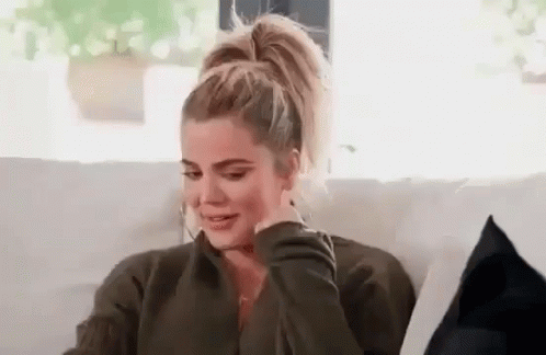 A Woman Is Sitting On A Couch With Her Hand On Her Face And Crying . GIF