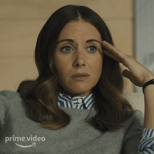 A Woman Is Sitting On A Couch With Her Hand On Her Forehead And The Word Prime Video Is On The Bottom GIF