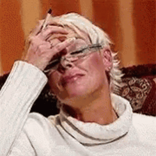 A Woman Is Sitting On A Couch With Her Hand On Her Forehead . GIF