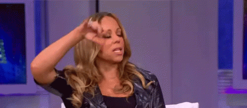 A Woman Is Sitting On A Couch With Her Hand On Her Head . GIF