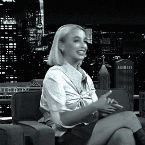A Woman Is Sitting On A Couch With Her Legs Crossed GIF