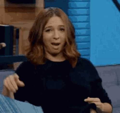 A Woman Is Sitting On A Couch With Her Mouth Open And Making A Funny Face . GIF