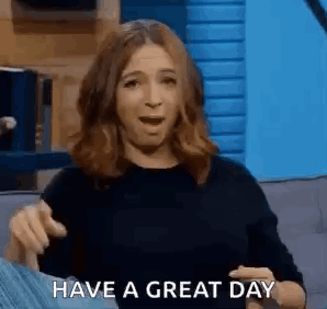 A Woman Is Sitting On A Couch With Her Mouth Open And Pointing At The Camera While Saying `` Have A Great Day '' . GIF