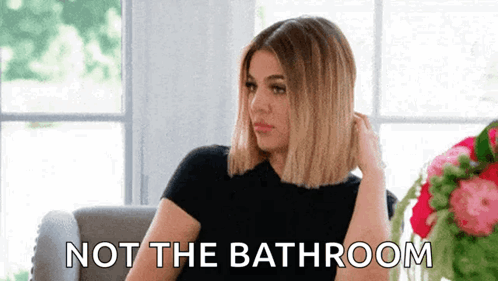 A Woman Is Sitting On A Couch With The Words Not The Bathroom Written On The Bottom . GIF