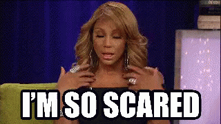 a woman is sitting on a green couch with her hands on her chest and the words `` i 'm so scared '' .