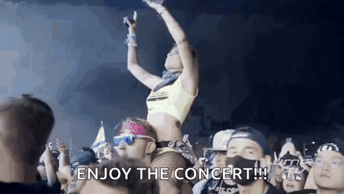 A Woman Is Sitting On A Man 'S Shoulders At A Concert Holding A Microphone . GIF