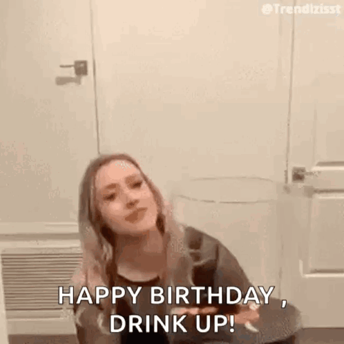 A Woman Is Sitting On A Toilet Holding A Glass Of Wine And Saying `` Happy Birthday , Drink Up '' . GIF