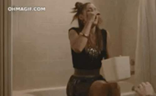 A Woman Is Sitting On A Toilet In A Bathroom With Blood On The Wall . GIF