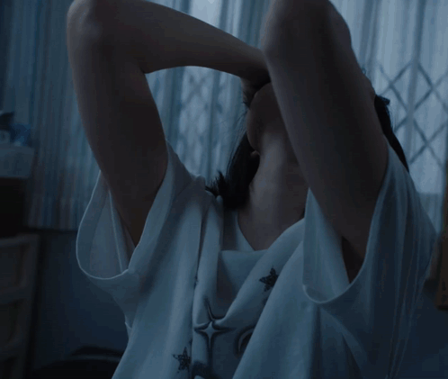 A Woman Is Sitting On An Escalator Holding Her Head In Pain GIF