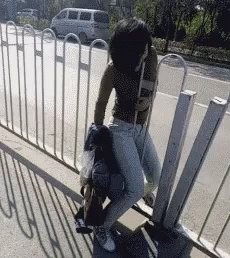 A Woman Is Sitting On Another Woman 'S Lap On A Sidewalk . GIF