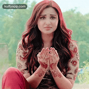 A Woman Is Sitting On The Ground With Her Hands Folded In Prayer . GIF