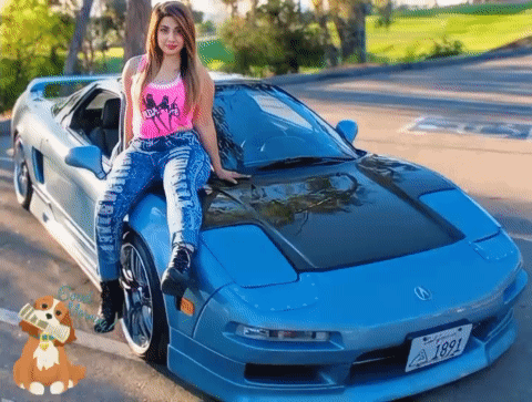 A Woman Is Sitting On The Hood Of A Blue Car With A License Plate That Says 1891 GIF