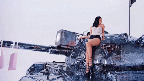 A Woman Is Sitting On Top Of A Giant Tank GIF