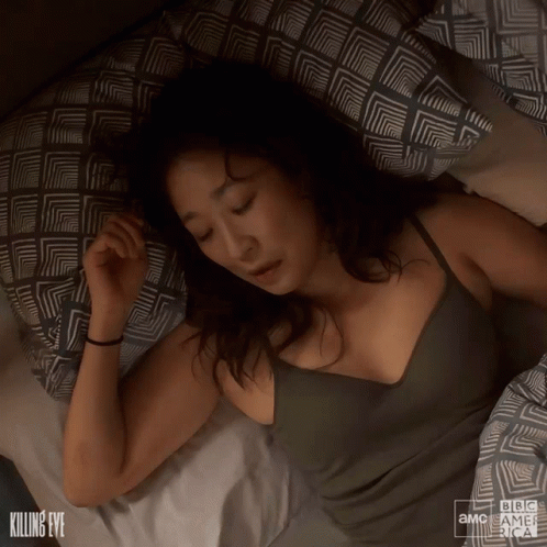 A Woman Is Sleeping On A Bed With A Bbc America Logo GIF