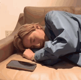 A Woman Is Sleeping On A Couch With A Cell Phone Next To Her . GIF