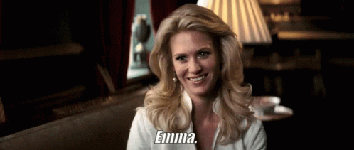 A Woman Is Smiling And Holding A Cup Of Coffee And The Word Emma Is On The Bottom Of Her Shirt . GIF