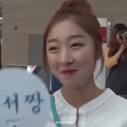 a woman is smiling and holding a fan with chinese writing on it