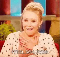 A Woman Is Smiling And Holding Her Hands To Her Chest . GIF