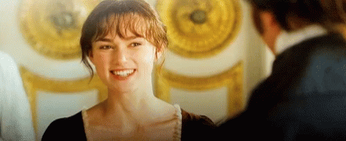A Woman Is Smiling And Looking At A Man In A Room . GIF