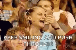 A Woman Is Smiling And Pushing Through A Crowd Of People In A Stadium . GIF