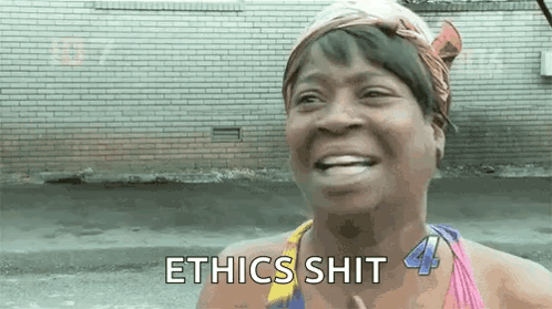 A Woman Is Smiling And Saying Ethics Shit In Front Of A Brick Building . GIF