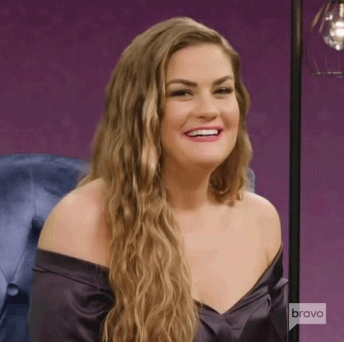 A Woman Is Smiling And Wearing A Purple Off The Shoulder Top . GIF