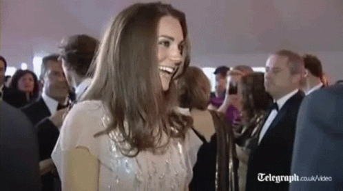 A Woman Is Smiling In A Crowd Of People At A Party . GIF