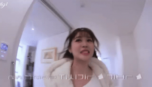 A Woman Is Smiling In A Hallway With Chinese Writing On The Bottom GIF