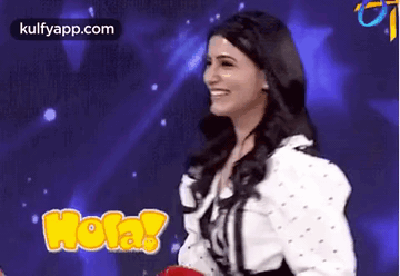 A Woman Is Smiling In Front Of A Blue Background While Holding A Red Balloon . GIF